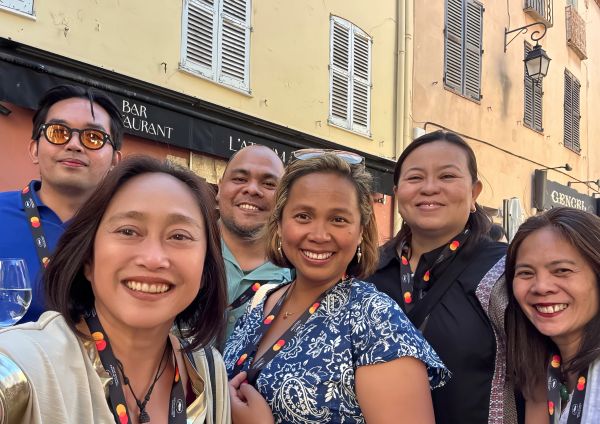 Group selfie of six people smiling outdoors.
