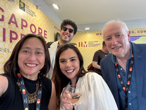 Group selfie of four people smiling at an event.