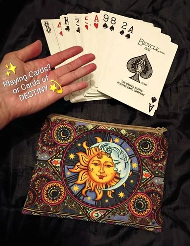 Hand holding playing cards with a sun and moon pouch.