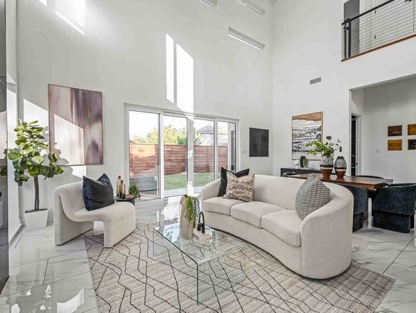 Bright modern living room with curved sofa and glass coffee table.