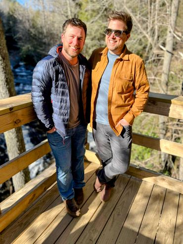 Husbands Todd and Rob standing by river in the North Georgia mountains winter