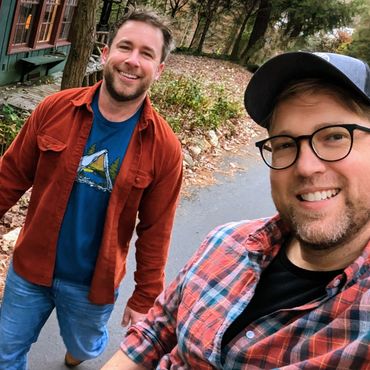 Husbands Rob wearing glasses and Todd coming from behind both grinning on a fall day