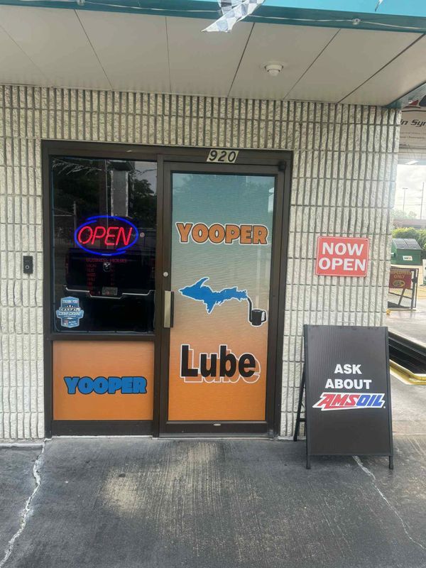 Entrance of Yooper Lube with signs indicating it's open and promoting AMSOIL.