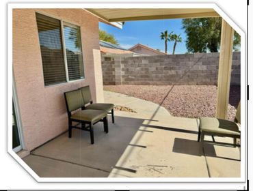 A quiet backyard patio with chairs and a stone-covered yard under a clear blue sky.