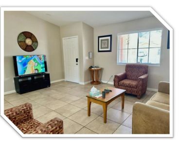 Cozy living room with patterned armchairs, a TV, and a wooden coffee table.