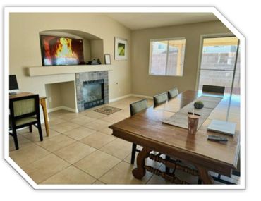 Dining room with a wooden table, chairs, and a fireplace with a TV above it.