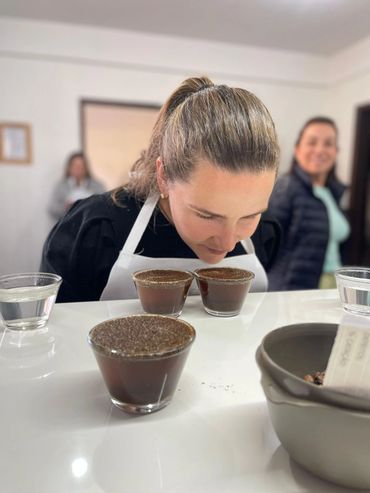 A woman smelling coffee grounds during a tasting session.