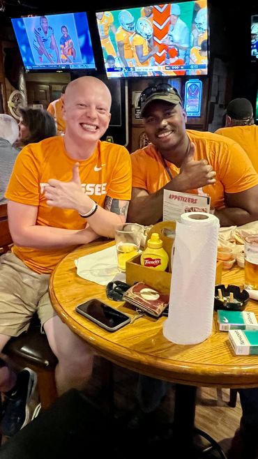 Patrons watching the UT Vols football game at a table with food and beer at Rooster's.