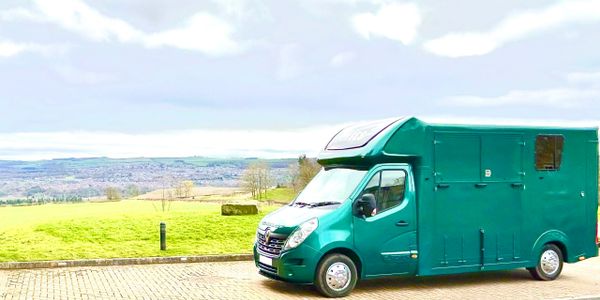 Green camper van parked near a scenic countryside overlook.