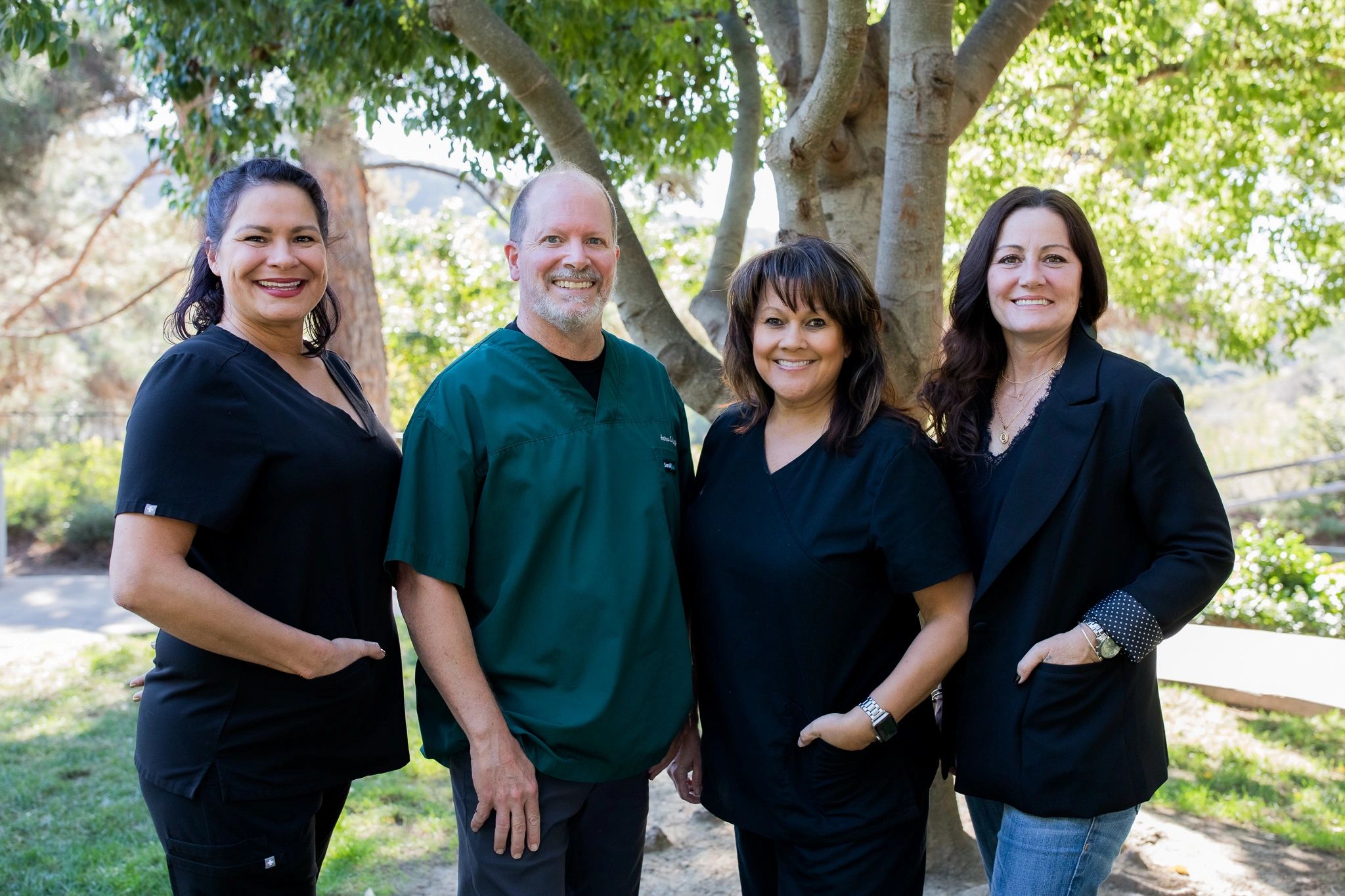 Softley Dental staff smiling and standing next to each other in a park 