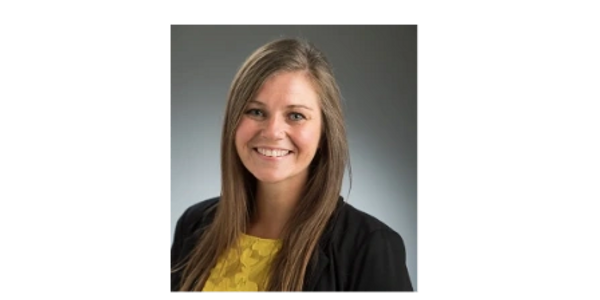 Headshot photo of Tessa Edwards wearing a yellow shirt with black jacket, hair down and smiling