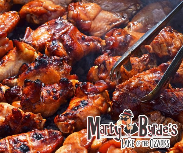 Grilled barbecue chicken wings being cooked with tongs at Marty Byrde's.