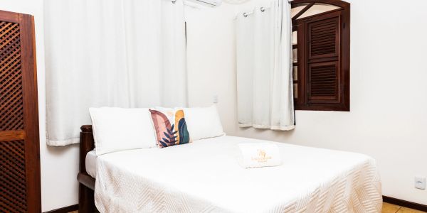 Cozy bedroom with white bedding and decorative pillow.