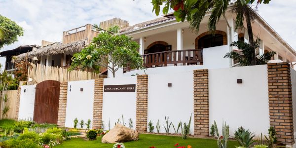 White and brick house with garden and wooden gate.