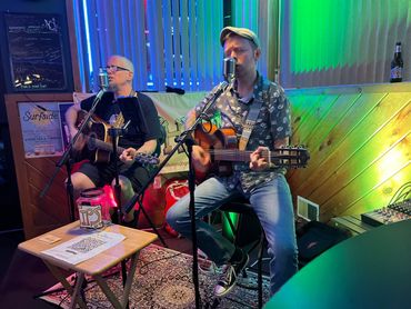 Two musicians performing with guitars in a cozy venue.