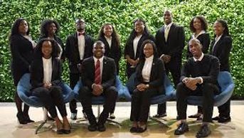 Group of professionals posing indoors against a leafy background.