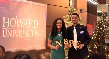 Two students posing with NSBE letters at Howard University event.