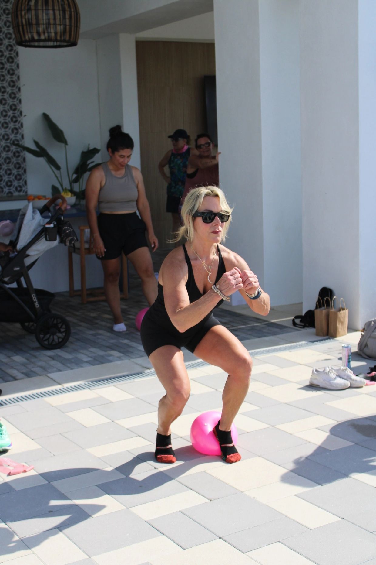Woman exercising outdoors balancing on a pink ball during a workout session.