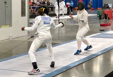 Two female fencers in a competition bout
