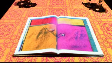 Open book on a vibrant patterned table with colorful images inside.