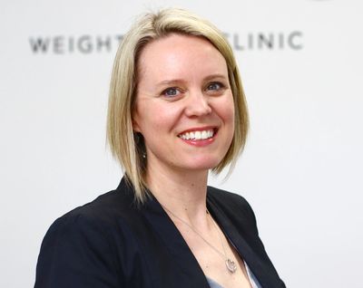 Smiling woman in professional attire at a weight loss clinic.