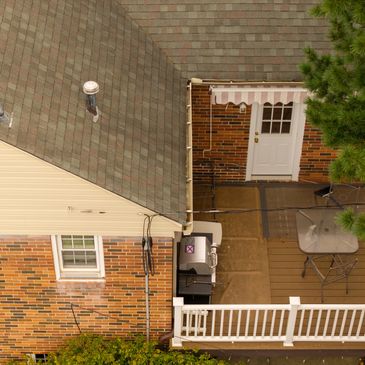 Top-down view of a backyard patio with grill, table, chairs, and white door.