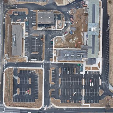 Aerial view of a commercial area with parking lots and buildings under construction.
