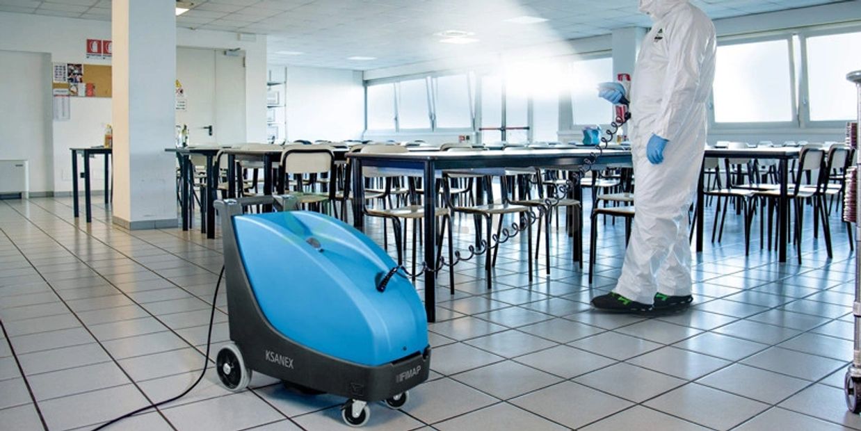 Person in protective suit cleaning a cafeteria with a blue machine.