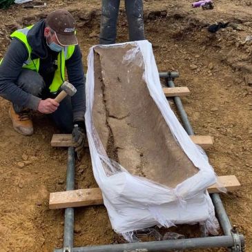 Archaeologists uncovering an ancient coffin.