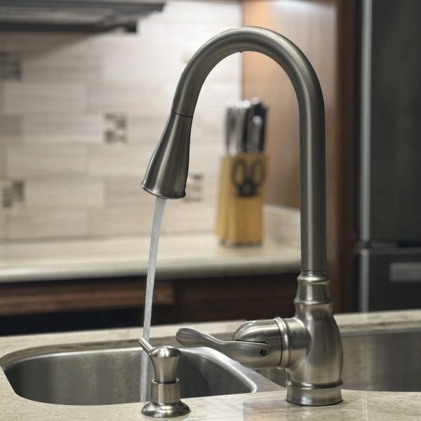 Modern kitchen faucet with water running over a granite countertop.