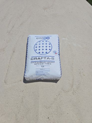 A 75 lb bag of white masonry cement on sand.