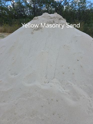 Pile of yellow masonry sand in an outdoor setting.