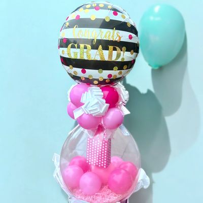 Colorful graduation balloon arrangement with pink and gold accents.