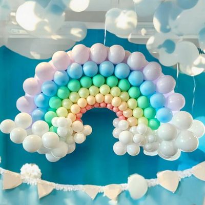 Colorful balloon rainbow decoration with white balloon clouds hanging indoors.