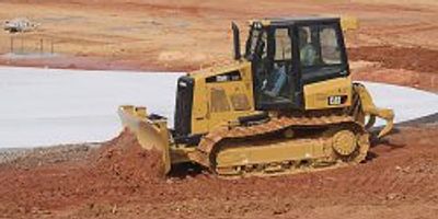 Yellow bulldozer moving earth on a construction site.
