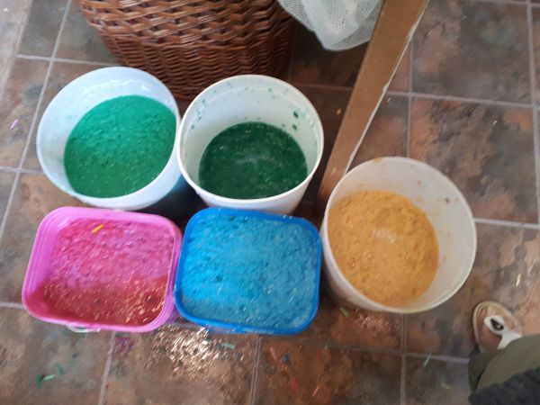 Buckets filled with colorful foamy liquid in green, blue, pink, and yellow.