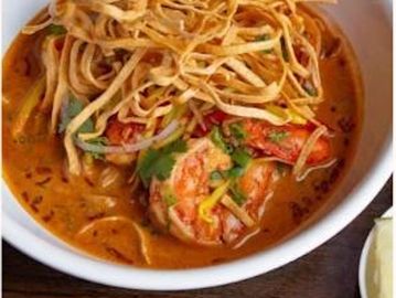 A bowl of shrimp curry topped with crispy fried noodles.