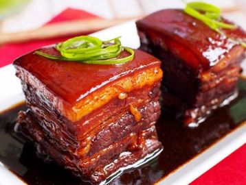 Two glossy, braised pork belly cubes garnished with green onions.