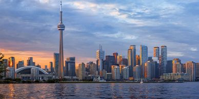 Toronto skyline with CN Tower at sunset over water.