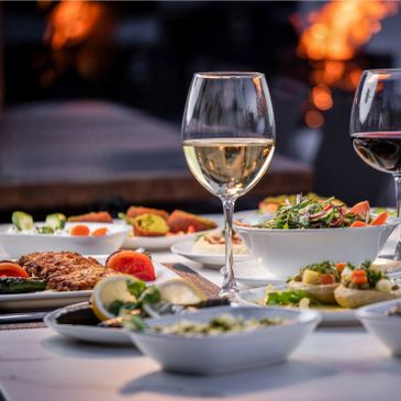 Elegant dinner setup with wine glasses and gourmet dishes on a white tablecloth.
