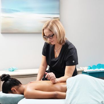 Massage therapist giving a back massage in a calm room.