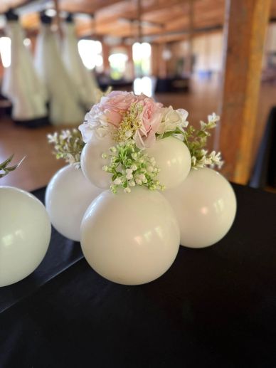 Elegant white balloons decorated with soft pastel flowers on a black table.