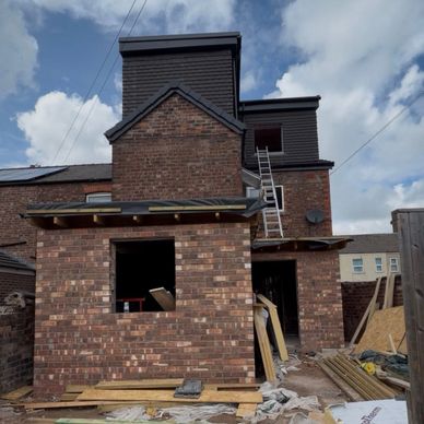 Brick house under construction with building materials scattered around.