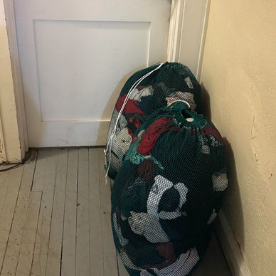 Two mesh laundry bags filled with clothes by a door.