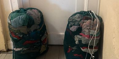 Two large mesh bags filled with clothes leaning against a door.