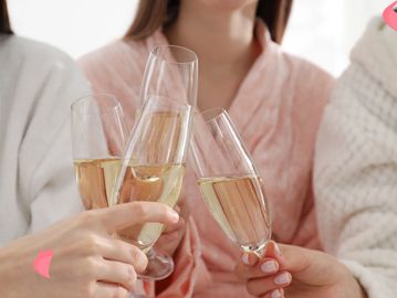 Women in robes clinking champagne glasses in a celebratory toast.