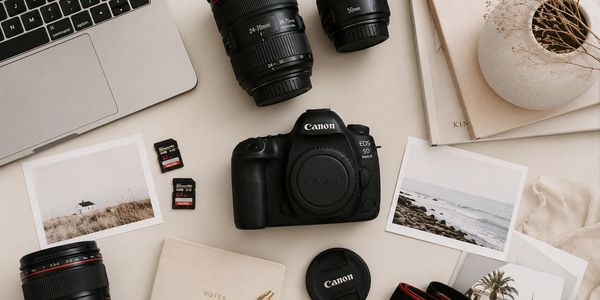 Photography gear including Canon camera, lenses, SD cards, and printed photos on a beige surface.