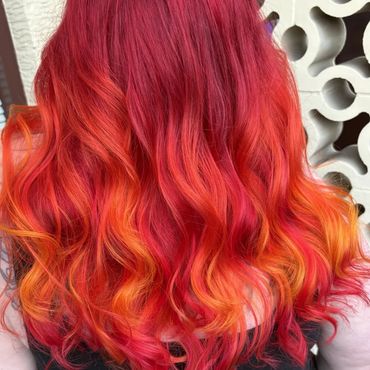 Vibrant red to orange ombre curls on long hair.