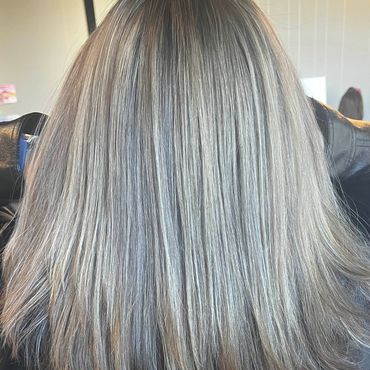 Back view of straight, layered silver-gray hair with dark roots.
