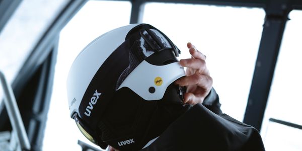 Person adjusting their white Uvex helmet indoors.